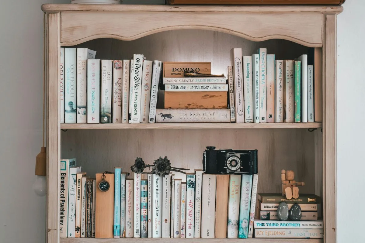 wooden bookshelf filled with classic English books arranged neatly in warm, rustic lighting