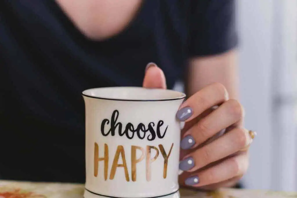 woman holding a white mug with the words "choose happy" written on it in gold and black letters