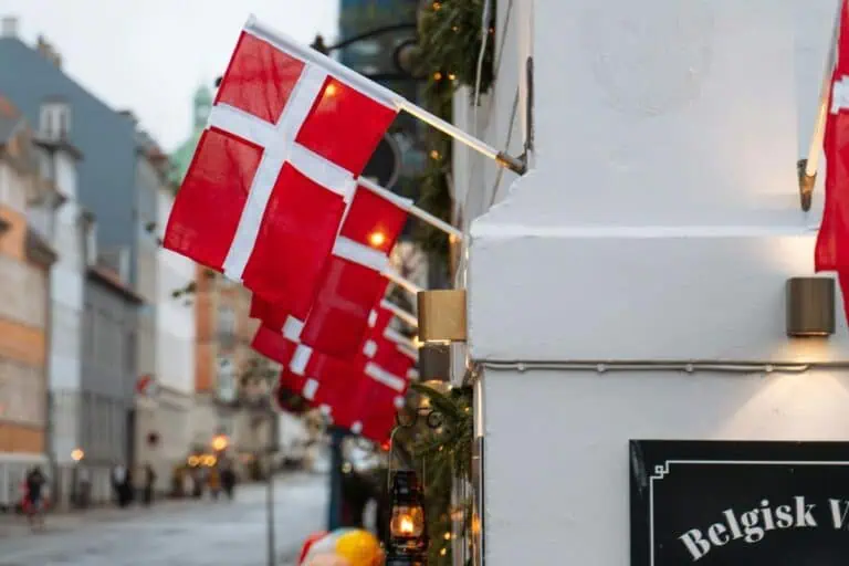 danish flags hanging along a quiet street in copenhagen with soft lights and old buildings in the background