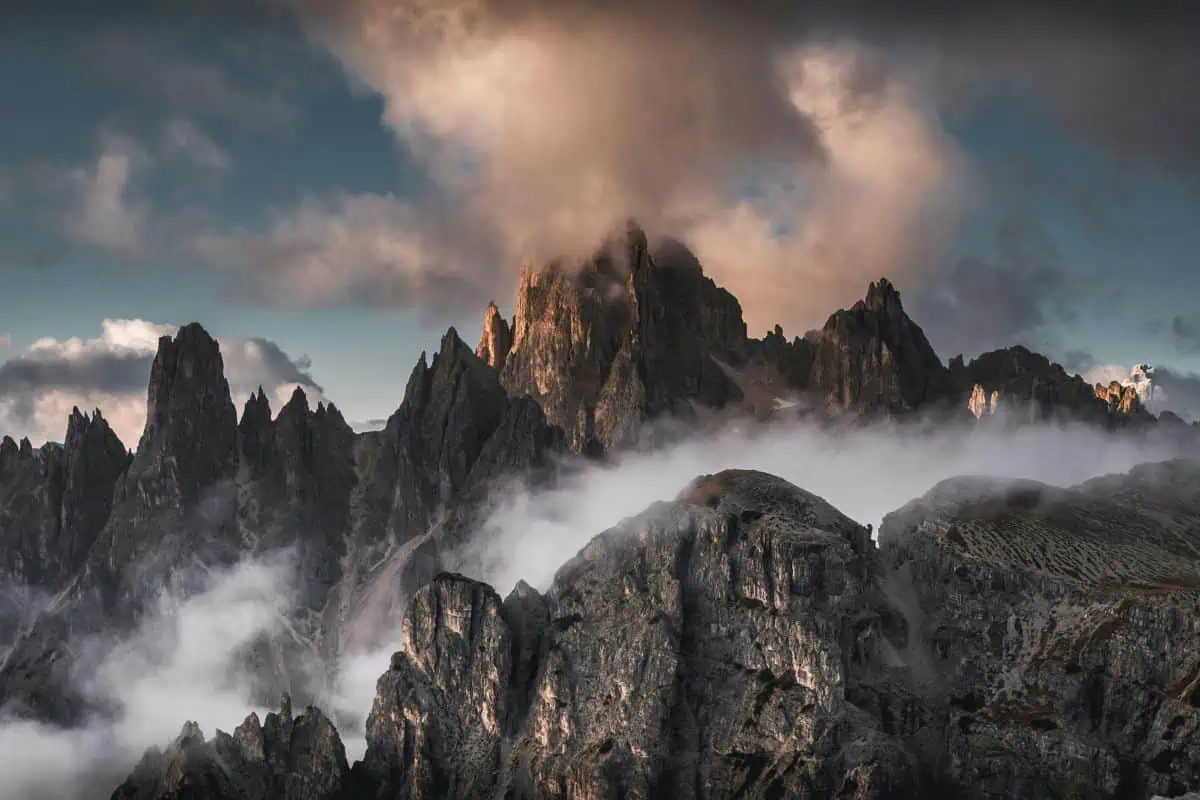 mist-covered rocky mountain peaks under dramatic clouds creating a powerful and quiet landscape perfect for mountain quotes