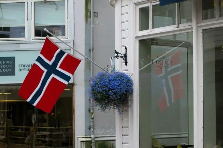 norwegian flag outside a scandinavian street building with blue flowers and white wooden walls